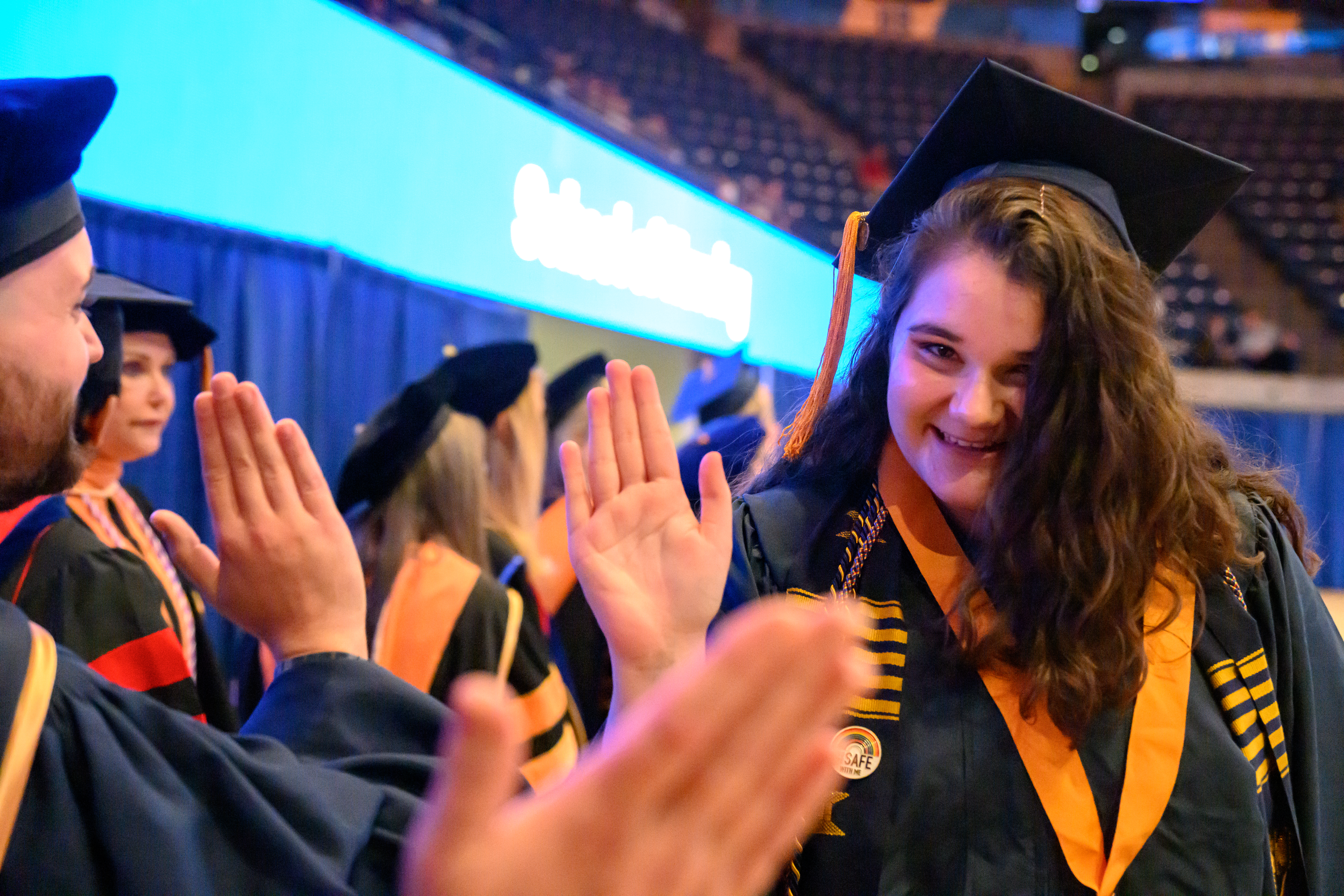 Nursing student in graduation regalia smiles and poses for a photo.