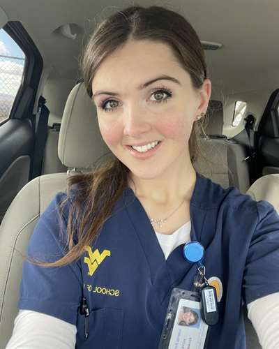 A selfie shows Serenity in her blue WVU School of Nursing scrubs.