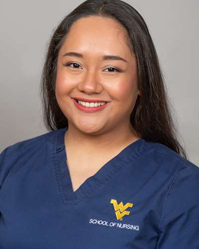 Katrina is seen smiling for the camera while wearing blue WVU School of Nursing scrubs.