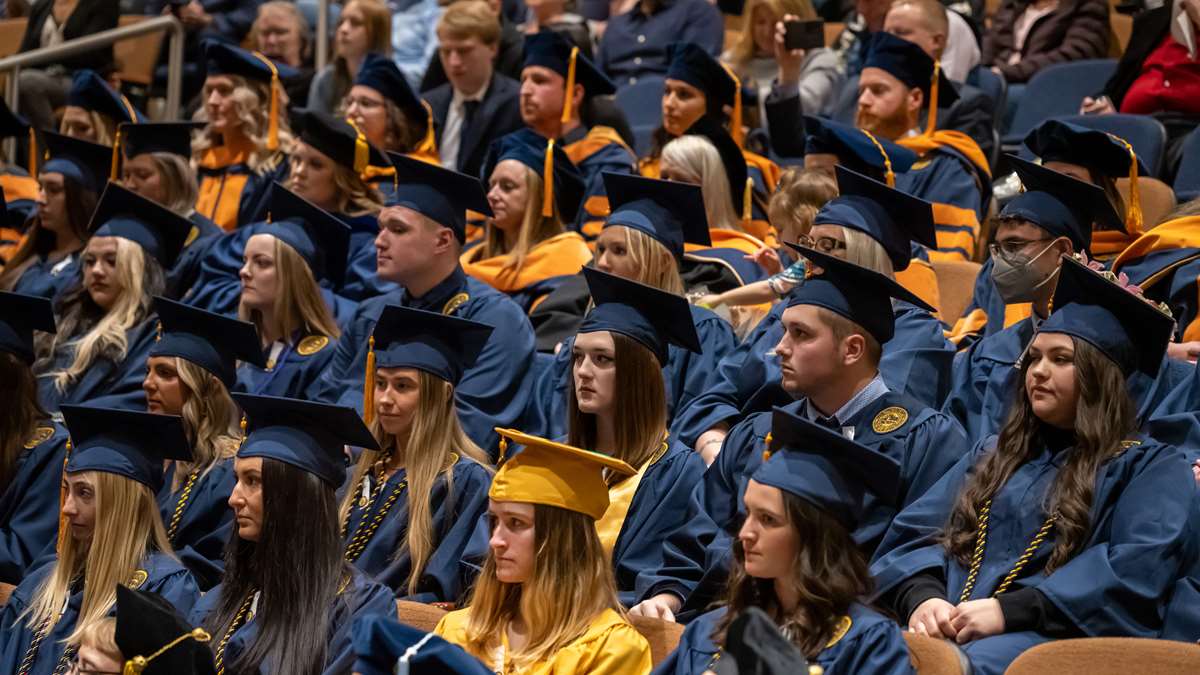 Graduates seated in an auditorium looking forward.