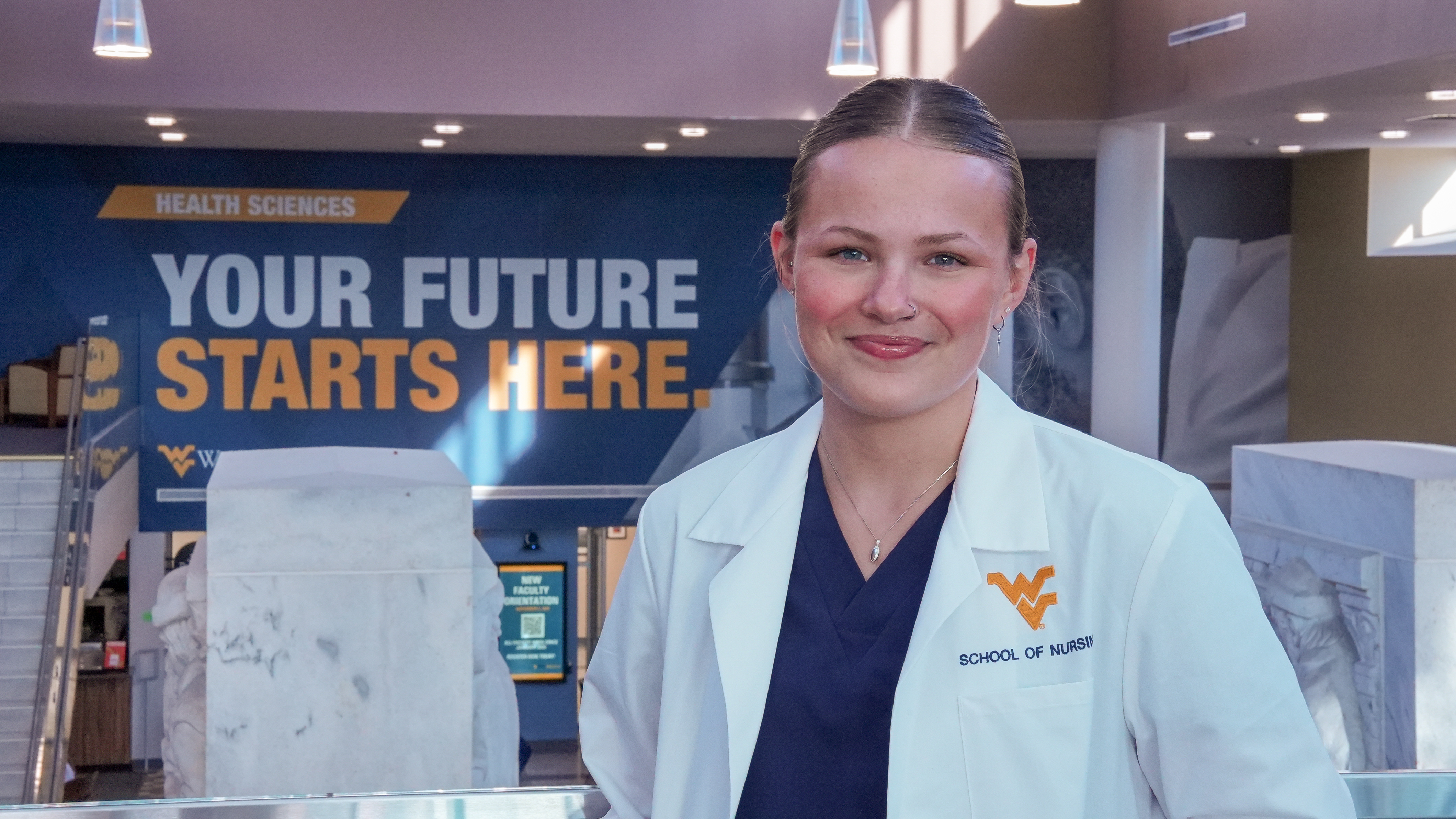 A nursing student poses for a photo at the Health Sciences Center Pylons before Pledge Ceremony.