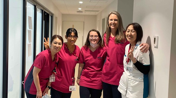 Nursing students in Japan work pose for a photo in a hallway.